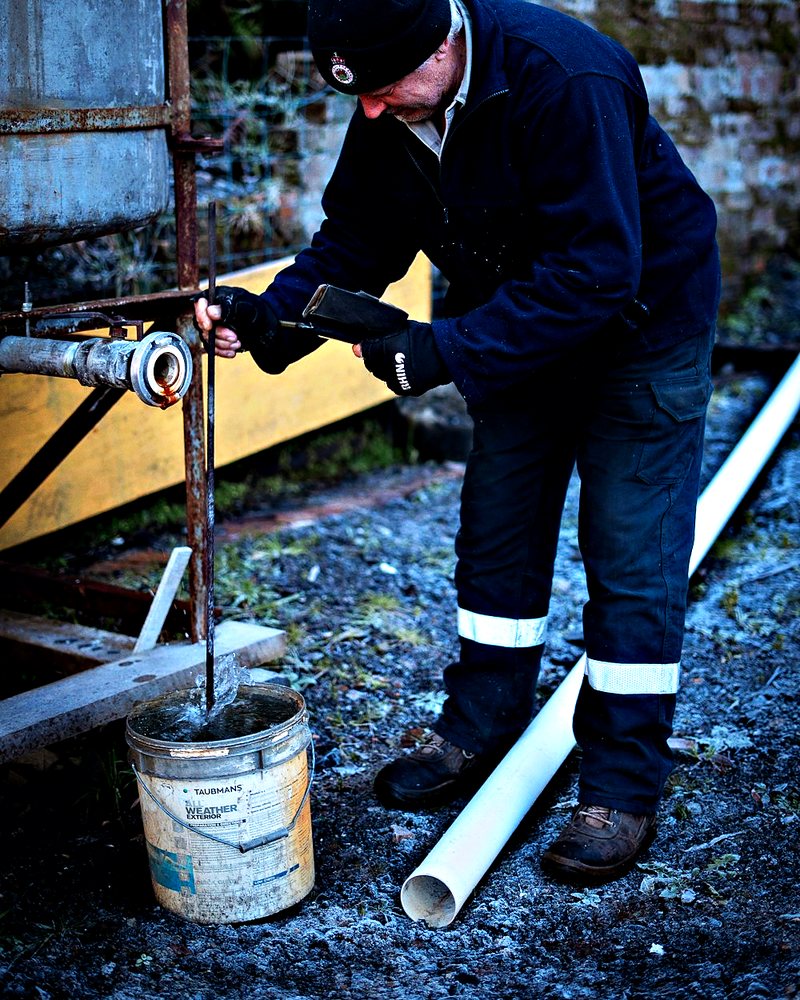 Vakman in werkkleding met reflectiestrepen aan het werk bij een waterleiding